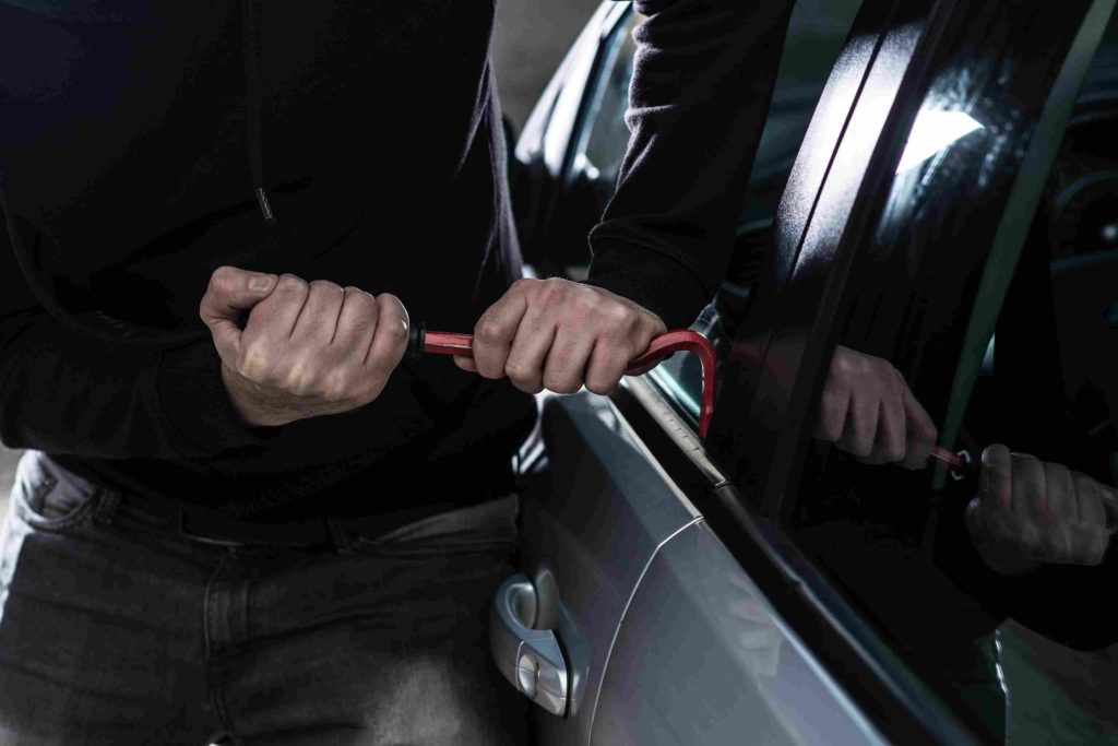 Person breaking into a car, representing vehicle theft felony in Colorado